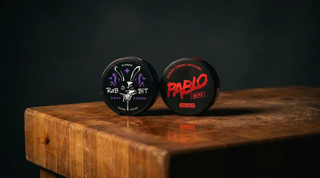 Rabbit and Pablo snus cans side by side on a butcher block table with dramatic low lighting